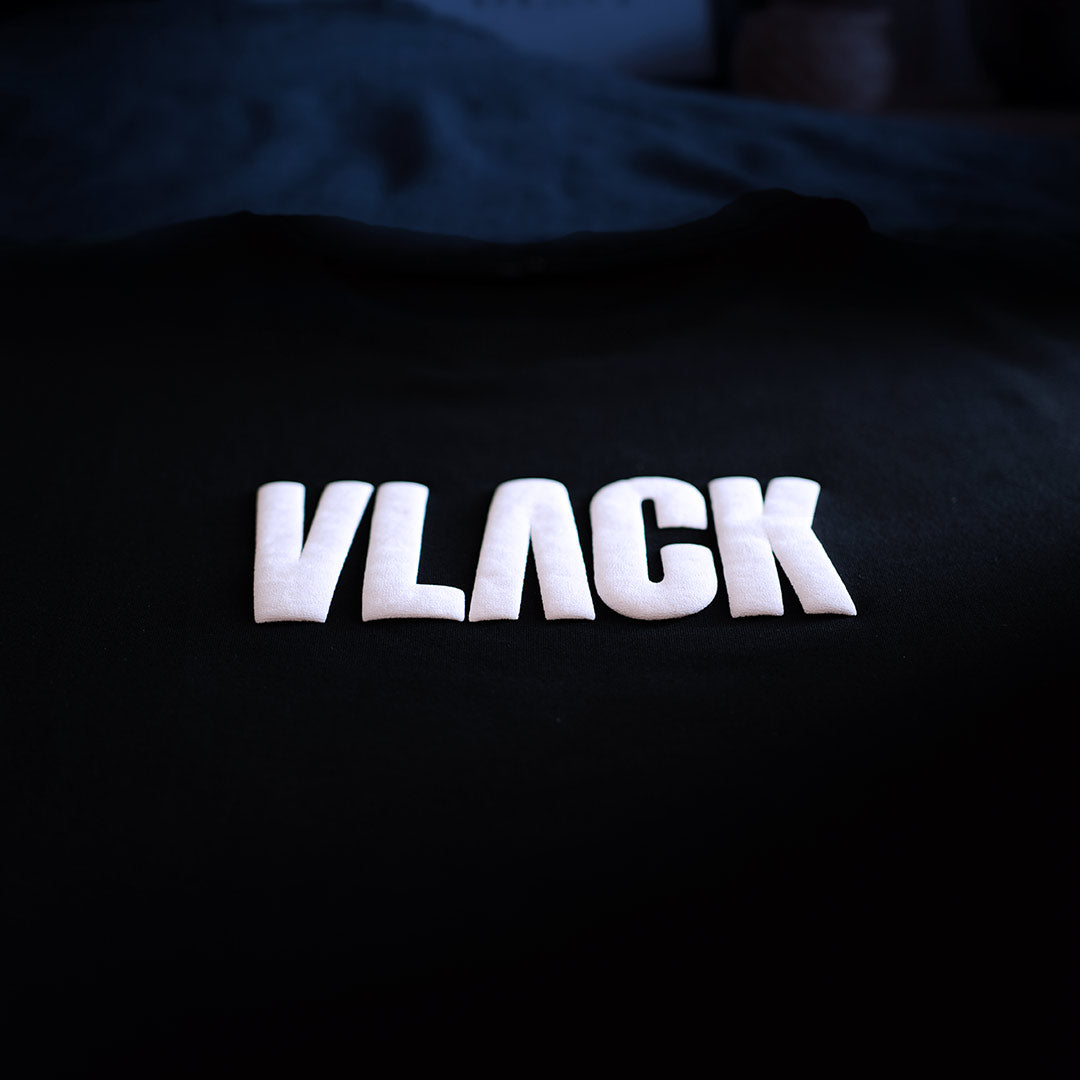 Vlack white logo on a black oversized streetwear t-shirt showing front chest print and relaxed oversized fit