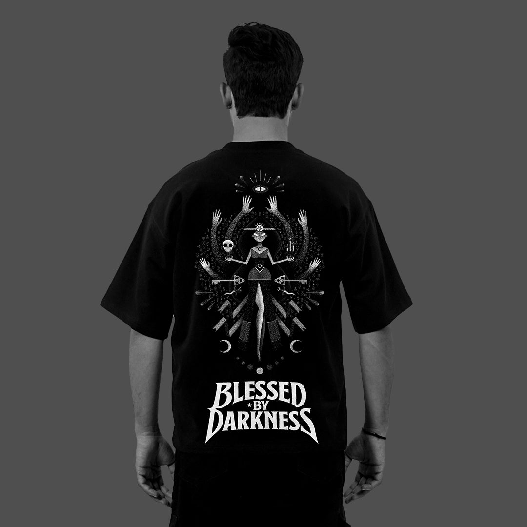 Back view of model wearing Vlack black oversized t-shirt streetwear with large white occult graphic and BLESSED BY DARKNESS text