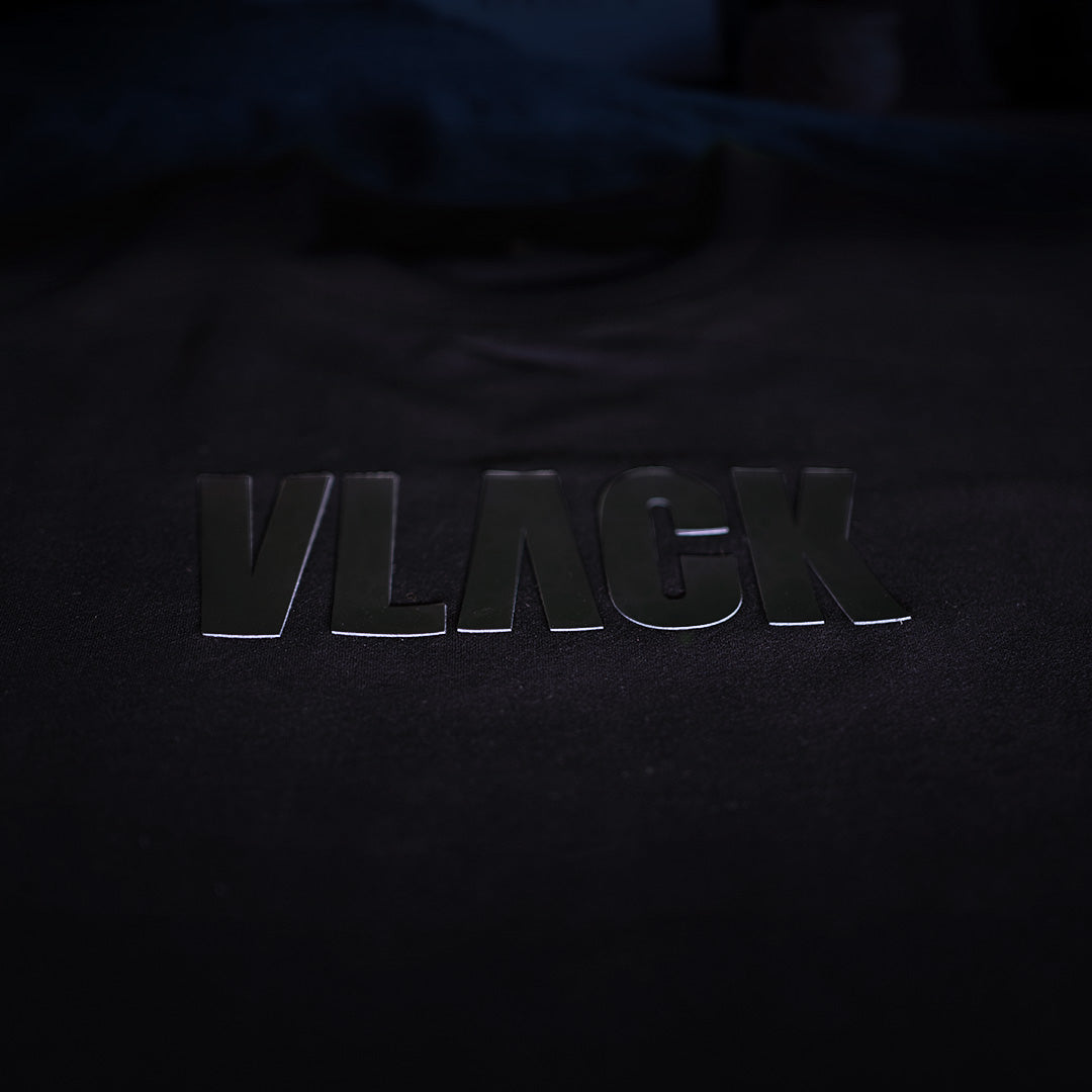 Closeup of Vlack black tee with glossy chest logo on cotton fabric for black panther oversize t-shirt streetwear look