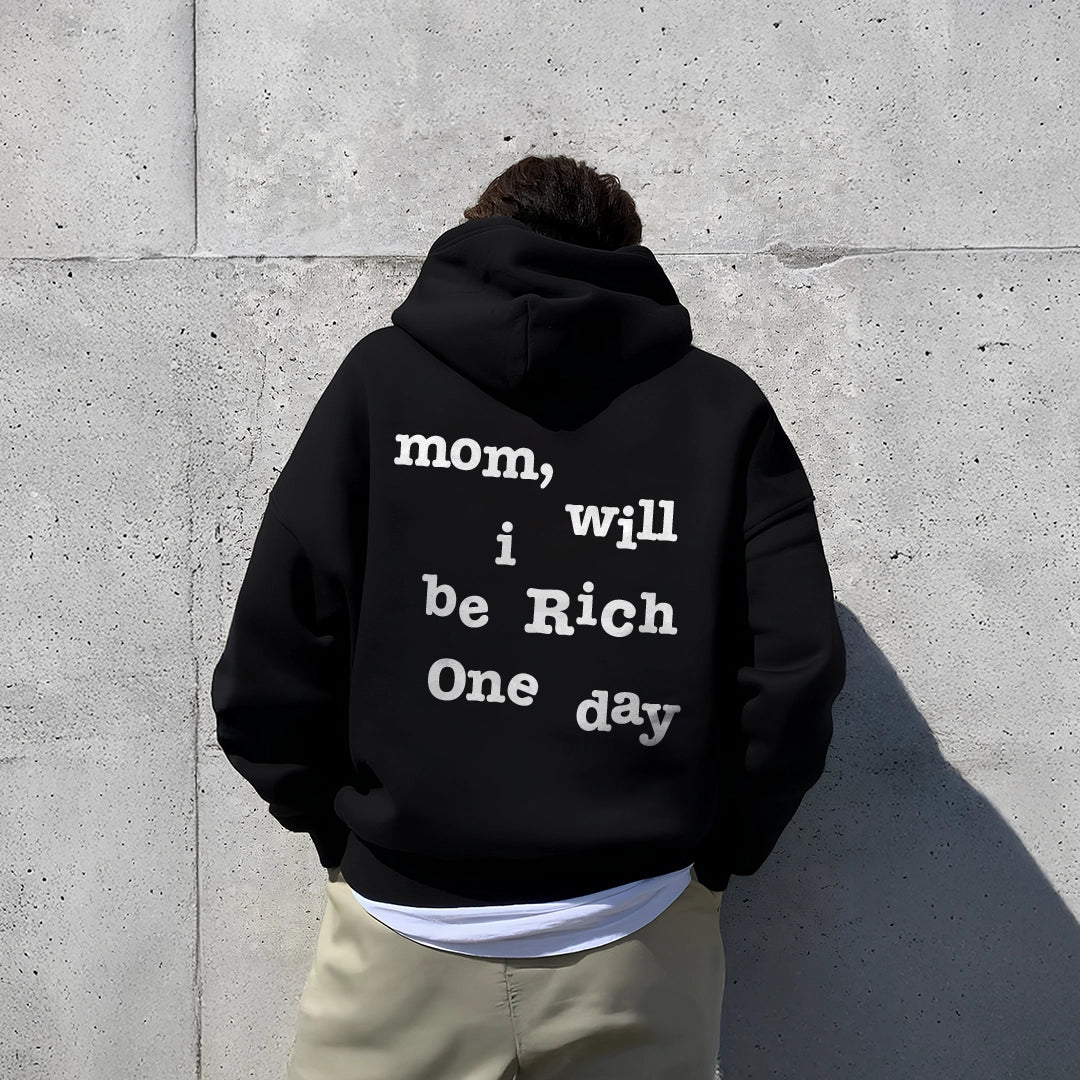 Oversized black hoodie featuring text 'mom, will be Rich One day' on the back for a trendy casual look