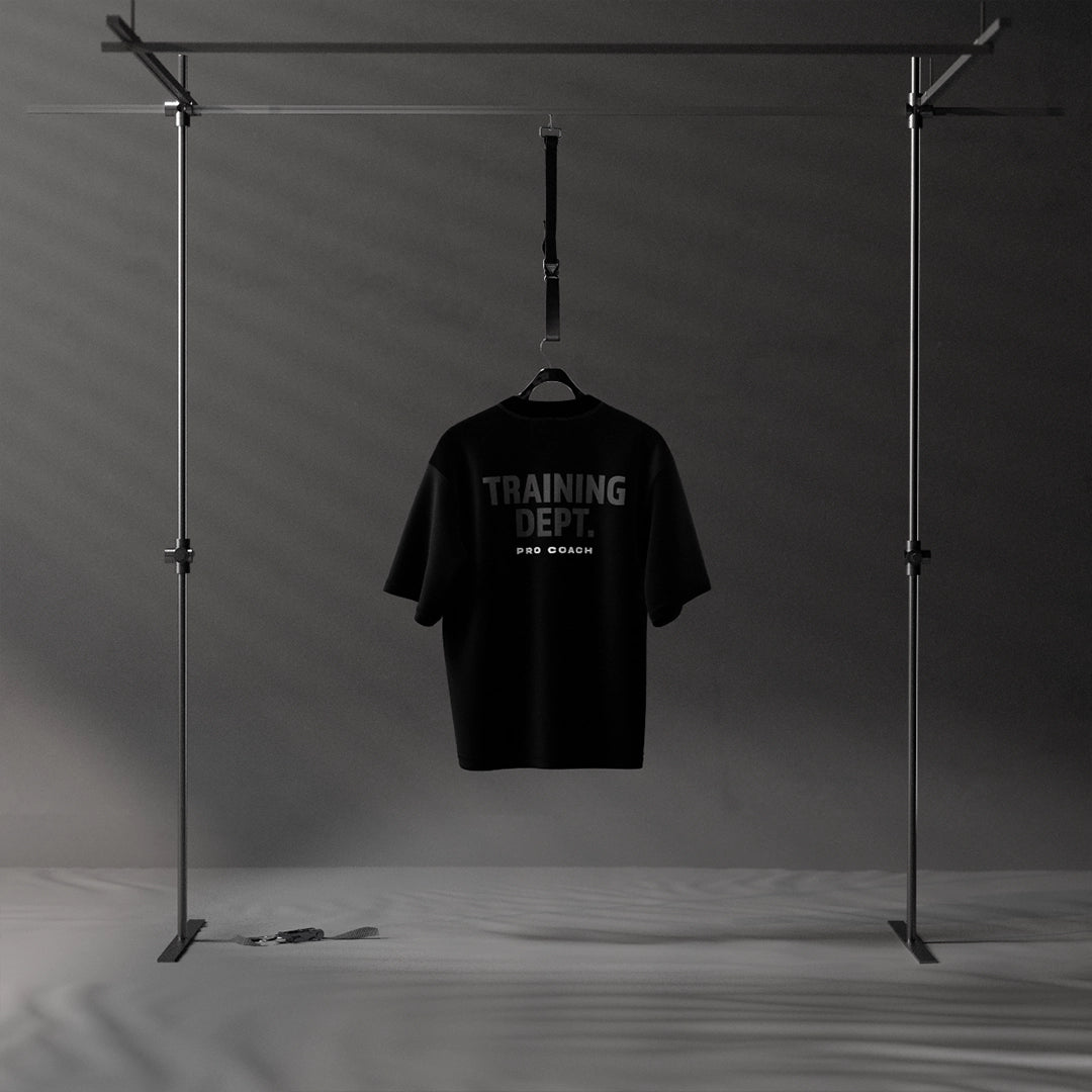 Black oversized streetwear t-shirt displayed on a hanger in a minimalist setting