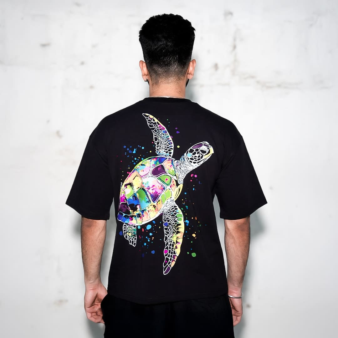 Rear view of man wearing Vlack black oversized streetwear t-shirt with colorful sea turtle graphic